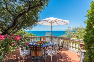 una mesa con sombrilla en un balcón con vistas al océano en Villa Dell'Angelo 10, Emma Villas en Rosignano Marittimo
