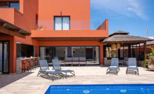 una casa con sillas y una piscina frente a ella en Villa privada de lujo con piscina Villa Wabi Sabi, en Corralejo