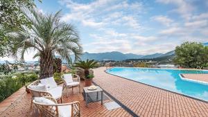 a swimming pool with chairs and a table and a palm tree at VILLA ELDA 6, Emma Villas in Loano