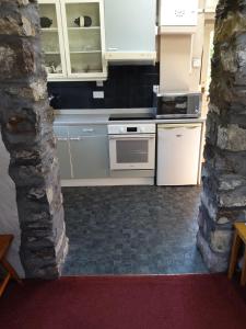 a kitchen with white appliances and a stone wall at Lile Cottage at Gleaston Water Mill in Ulverston