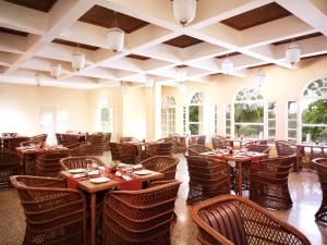 a restaurant with wooden tables and chairs and windows at Gir Serai - IHCL SeleQtions in Sasan Gir