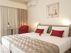 una habitación de hotel con una cama grande con almohadas rojas en Hotel Galaxias, en Rodas