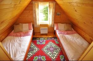 two beds in a attic room with a window at Chalet Escapade with Sauna in Žabljak