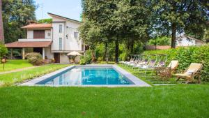 einen Pool in einem Garten mit Stühlen und einem Haus in der Unterkunft VILLA LA MERIDIANA 8&1, Emma Villas in Pietrasanta