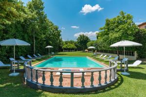 una piscina con sillas y sombrillas en un patio en VILLA DELLE SOPHORE 16&4, Emma Villas en Cortona