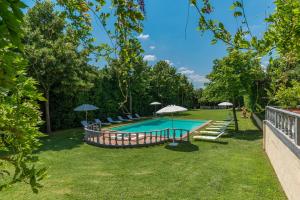 a swimming pool with chairs and umbrellas in a yard at VILLA DELLE SOPHORE 16&4, Emma Villas in Cortona