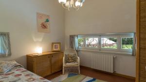a bedroom with a bed and a chair and a window at VILLA LA MERIDIANA 8&1, Emma Villas in Pietrasanta