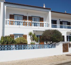 a white house with blue balconies and plants at Casa Boa Onda in Sagres