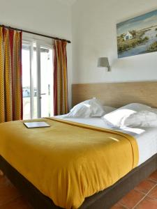 1 cama con manta amarilla y ventana en Mas de la Grenouillère Hôtel et Centre équestre en pleine nature, en Saintes-Maries-de-la-Mer