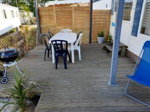 un patio con mesa, sillas y parrilla en Location mobil home, en La Baule