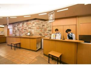 two people standing at a counter in a waiting room at R&B Hotel Nagoya Nishiki - Vacation STAY 15159v in Nagoya