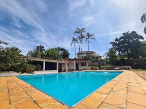 una piscina frente a una casa con palmeras en Rancho da Serra Pousada, en Tiradentes