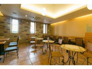 um quarto com mesas e cadeiras e uma parede de tijolos em R&B Hotel Nagoya Nishiki - Vacation STAY 15171v em Nagoia