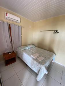 um pequeno quarto com uma cama e uma mesa de cabeceira em Chico do Caranguejo Praia da Baleia em Itapipoca