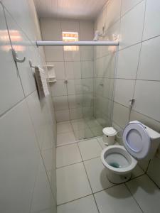 La salle de bains blanche est pourvue d'une douche et de toilettes. dans l'établissement Chico do Caranguejo Praia da Baleia, à Itapipoca