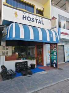 Hostal La Casa de Luis في بويرتو بكويريزو مورينو: مبنى مستشفى مع مظلة زرقاء وبيضاء