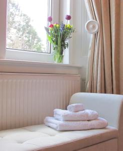 a pile of towels sitting on a chair in front of a window at Arden House in Kingussie