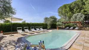 a swimming pool with lounge chairs and a table and a table at Virginia 8, Emma Villas in Gavorrano