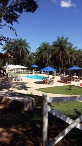 uma piscina com mesas e guarda-sóis azuis num parque em Chalés do Recanto em São João del Rei