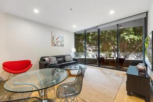 a living room with a glass table and chairs at Docklands 2-Bed Near CBD & Marvel Stadium in Melbourne