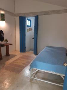 Un dormitorio con una cama azul y una puerta en Pousada Casa da Praia Itaúnas en Itaúnas