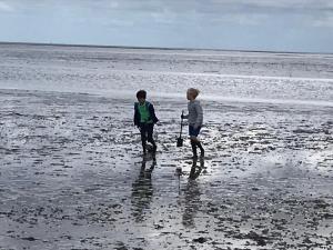 two children are walking on the beach at Haus Klaarstrand in Wenningstedt