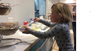 a little girl holding a plate of food in a kitchen at Haus Klaarstrand in Wenningstedt