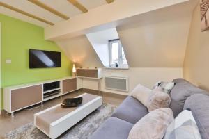 a living room with a couch and a tv at Gîte -Coup de Cœur- 3 étoiles in Turckheim