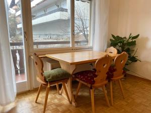 drewniany stół i krzesła w pokoju z oknem w obiekcie Sonnalpine Apt 12 - Managed by TheSelectionist w Sankt Moritz