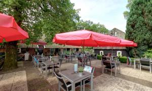 een patio met tafels en stoelen met rode parasols bij Hotel Boerderij Restaurant De Gloepe in Diffelen