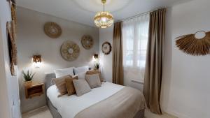 1 dormitorio con cama blanca y lámpara de araña en Casa Tulum en Irigny