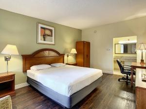 a bedroom with a large bed and a desk and a table at Stayable Orlando at Florida Mall in Orlando