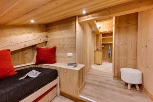 Dormitorio en cabaña de madera con cama y silla en Chalet Mon Idole, en Flumet