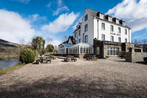 a large white building with picnic tables in front of it at Killin Hotel in Killin