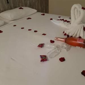 a white bed with a bottle of lipstick and hearts on it at Areia do Atlantico Hotel in Porto Seguro
