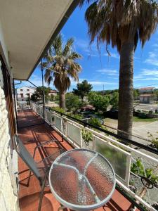 einen Balkon mit einem Tisch, Stühlen und einer Palme in der Unterkunft APARTMANI 4 PALME in Starigrad-Paklenica