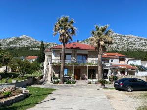 a house with palm trees and a car parked in front at APARTMANI 4 PALME in Starigrad-Paklenica