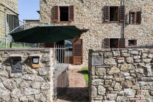 una sombrilla verde frente a un edificio de piedra en IL POZZO SUL COLLE, en Rigomagno