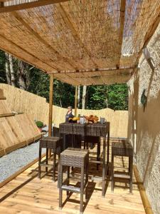 a wooden table and chairs under a wooden pergola at Maisonnette A Santa Ghjulia entre Mer & Montagne in Volpajola