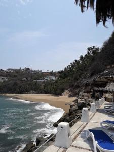 a beach with a bunch of chairs and the ocean at Puerto Las Hadas Apartamentos 1065-1063-764 in Manzanillo +11 photos