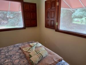 a bedroom with two towels on a bed with two windows at Chalé Veredas e Buritis in Pirenópolis