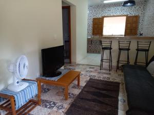 a living room with a tv and a table with a fan at Chalé Veredas e Buritis in Pirenópolis