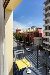 a yellow chair on a balcony with a parking lot at Apartamentos enfrente del Museo Dalí - Serena Stays in Figueres
