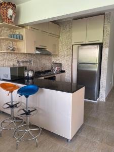 a kitchen with a counter and two stools at شاليه أرضي بجنينه في مارينا وادي دجله العين السخنه Three Bedroom Chalet with Garden In Marina Wadi Degla Ain El Sokhna - For Families Only in Ain Sokhna