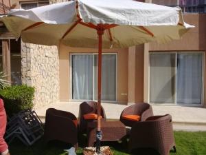 a table and chairs with an umbrella in a yard at شاليه أرضي بجنينه في مارينا وادي دجله العين السخنه Three Bedroom Chalet with Garden In Marina Wadi Degla Ain El Sokhna - For Families Only in Ain Sokhna +4 photos