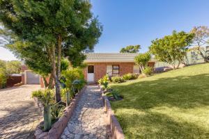 a brick house with a garden in front of it at Perlemoen Retreat in Herolds Bay