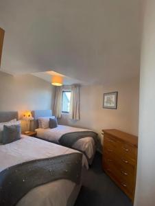a bedroom with two beds and a dresser and a window at Harbour View & Beach 50m from doorstep! in Nairn