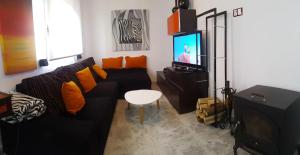sala de estar con sofá negro y TV en Casa de Playa Pet Friendly, en Virxe das Mareas