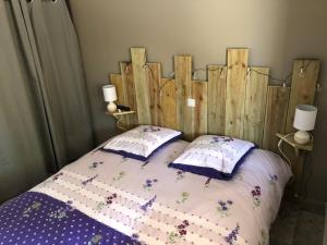a bedroom with a wooden headboard and a bed with pillows at Cottage piscine intérieure31degrés ZOO LA FLECHE24H du Mans in Clermont-Créans