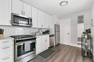 una cocina con armarios blancos y electrodomésticos de acero inoxidable en Completely Set-Up 3BR Apt near Shops & Dining! - Lincoln 3 en Chicago